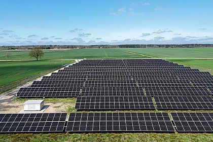 Saules baterijas, lauks ar zaļu zāli, zilas debesis